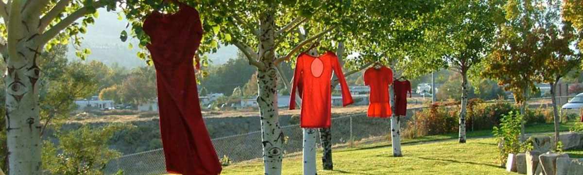 Two red dresses and two orange dresses hanging from four individual trees respectively