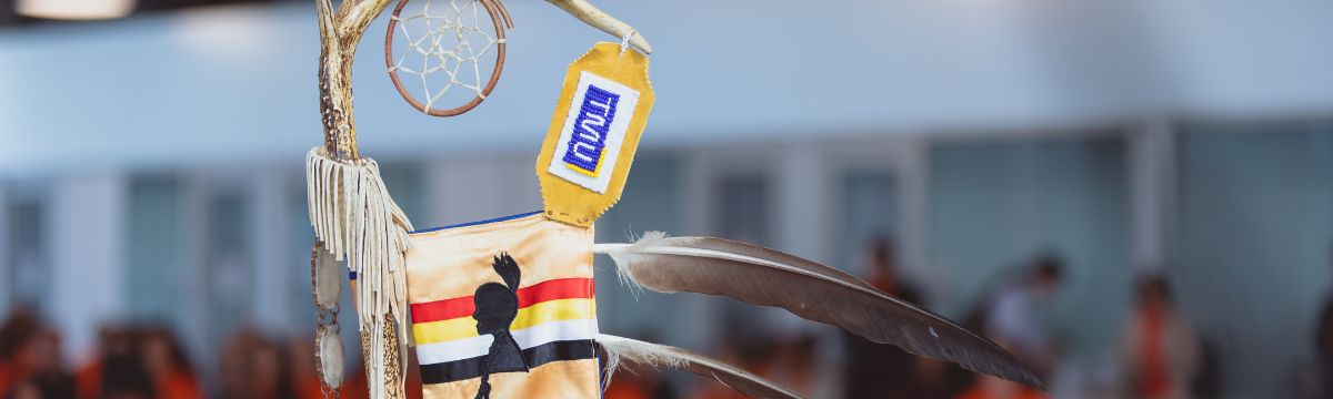 Part of the Eagle Staff, including three feathers and red, yellow, white and black ribbons