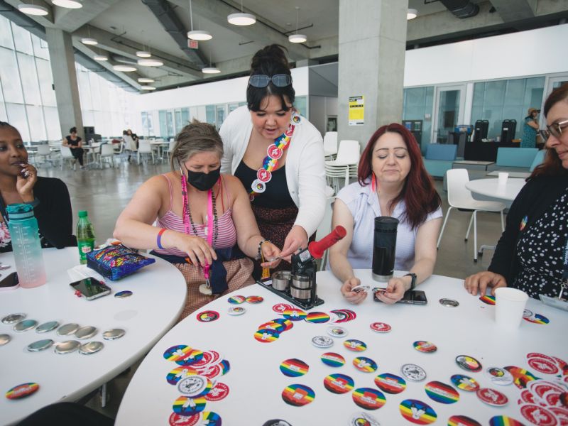  A group of community members sit at a table together making buttons.