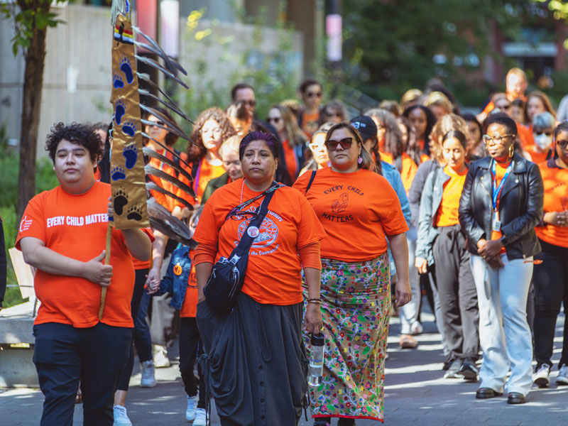 Members of the TMU community at the 2023 memorial walk. At the front of the group, a staff member holds the TMU Eagle Staff.