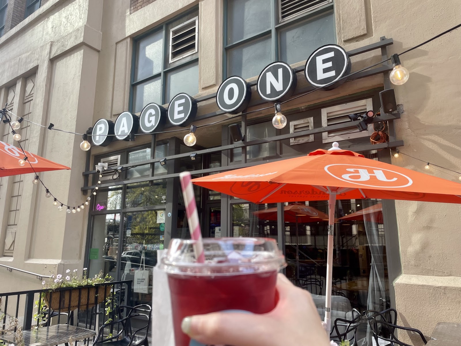 Jennifer holding a drink in her hand, the Page One cafe entrance and sign can be seen in the background.
