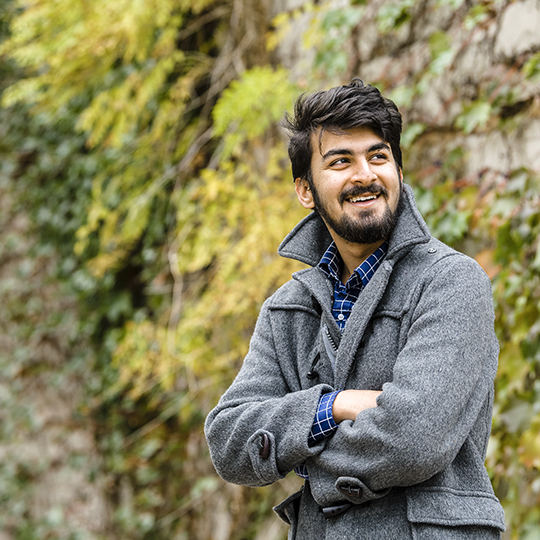 Abhi Rajeha in front of a vine covered building