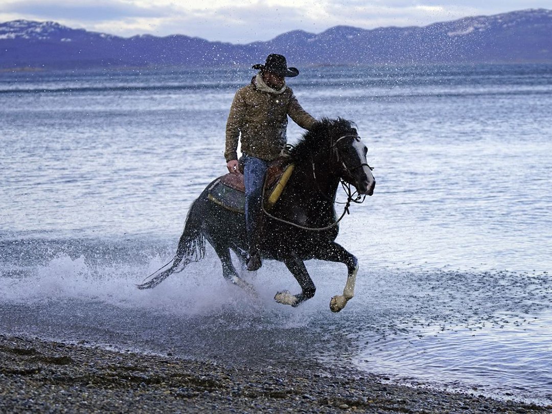 Filipe Masetti Leite riding a horse on the beach. 