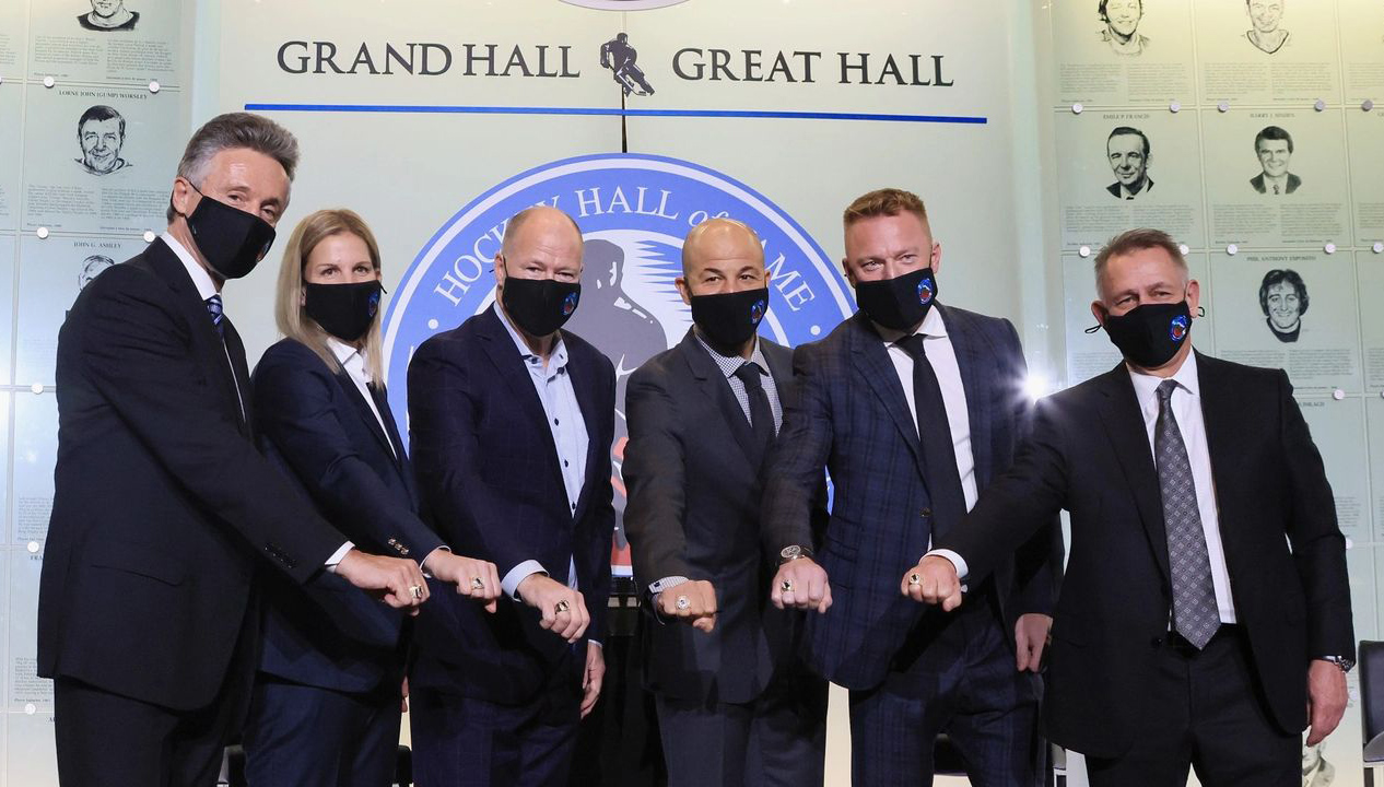 Group of people all wearing black face masks put their fists into the middle.