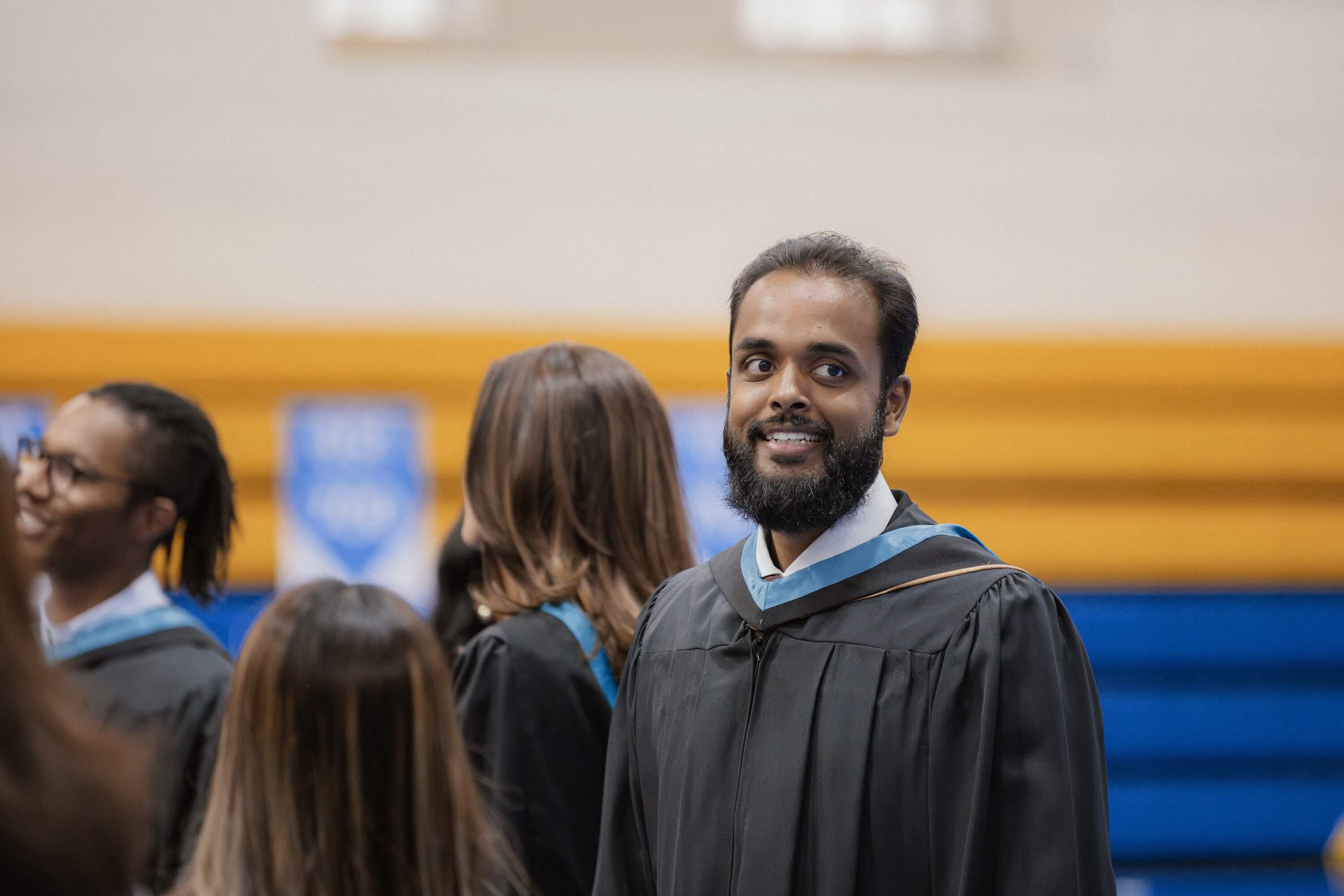 A graduate standing and smiling at Convocation.