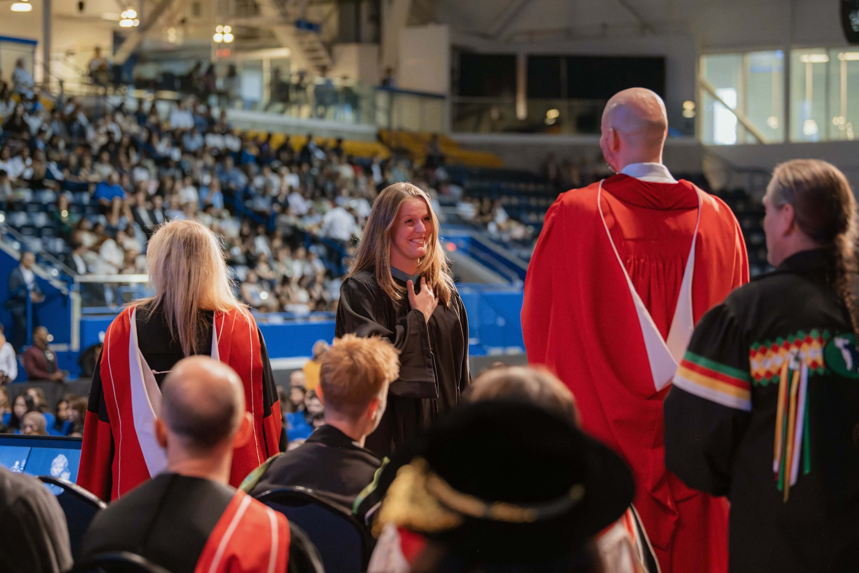 A woman with her hand on her heart walking across the stage at Convocation.