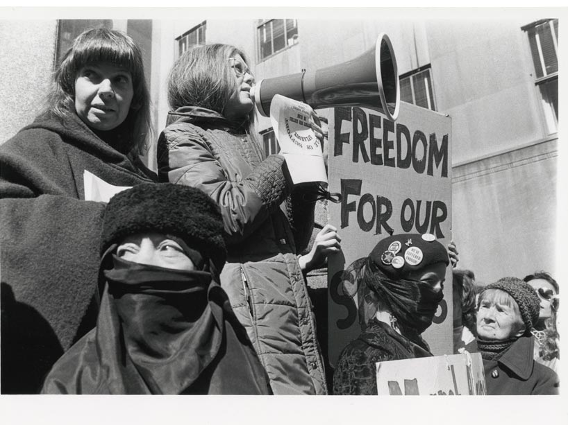 Black and white photo of woman shouting into a megaphone, protesting women’s rights