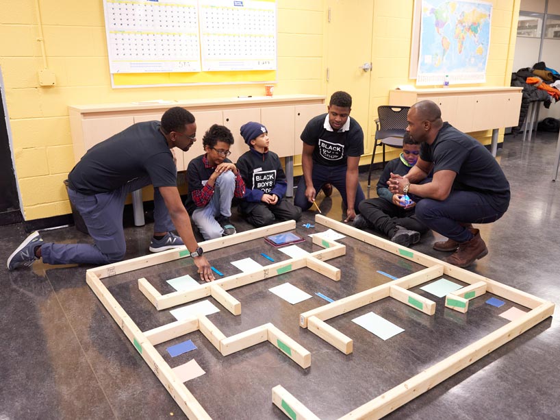 Six Black male youths collaborating on a wooden mini obstacle course