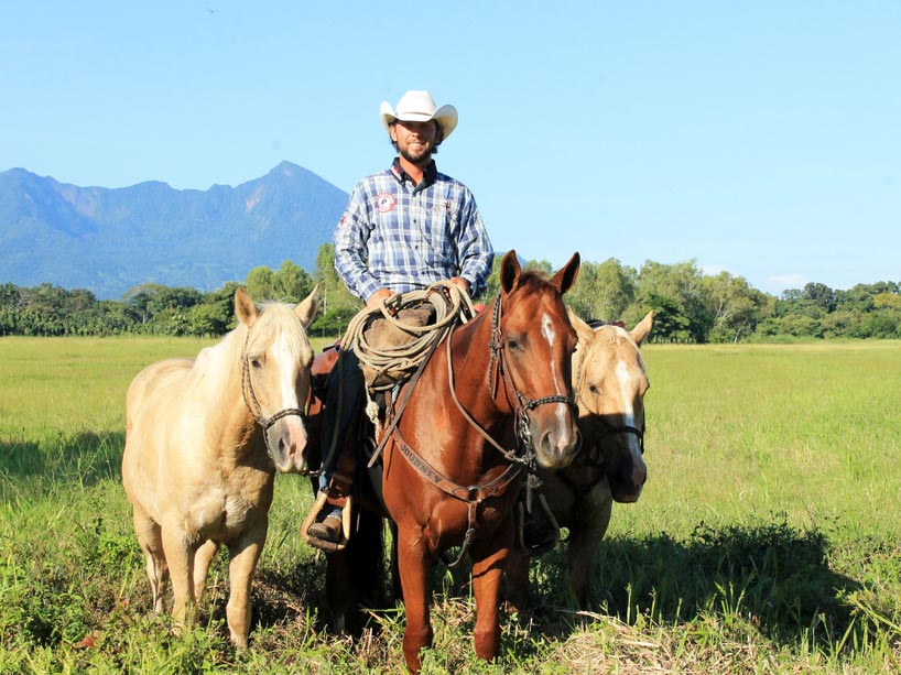 Filipe Masetti Leite with his three horses, sitting on the one in the middle, in an open field