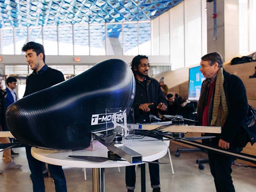 Small-scale model of flying vehicle with team members talking in background