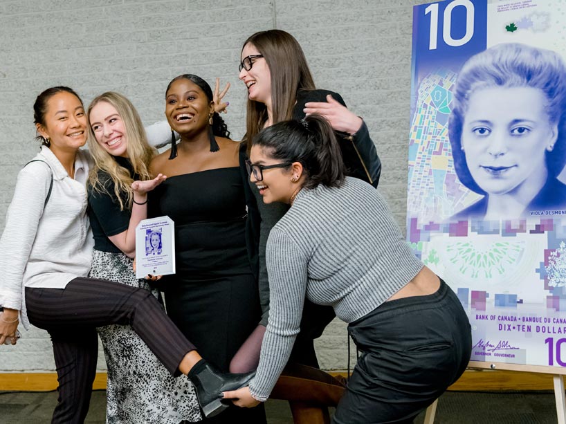 Woman in centre holding award with four friends around her