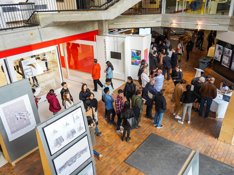 Overhead shot of crowd at architectural science exhibit, lining up to speak to hosts at table