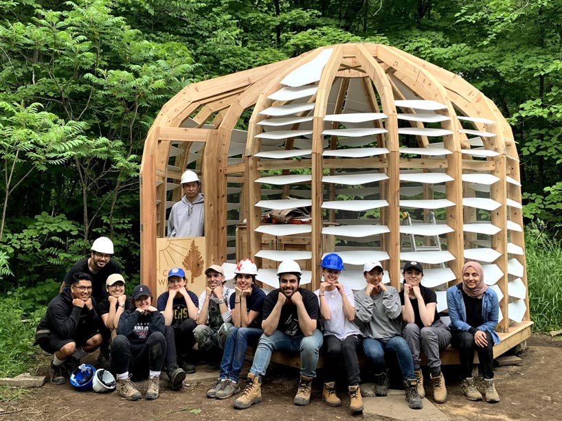 The student team sitting in front of the wooden structure