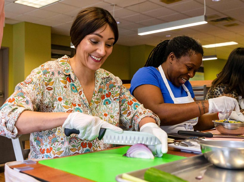 Two women laughing, slicing onions