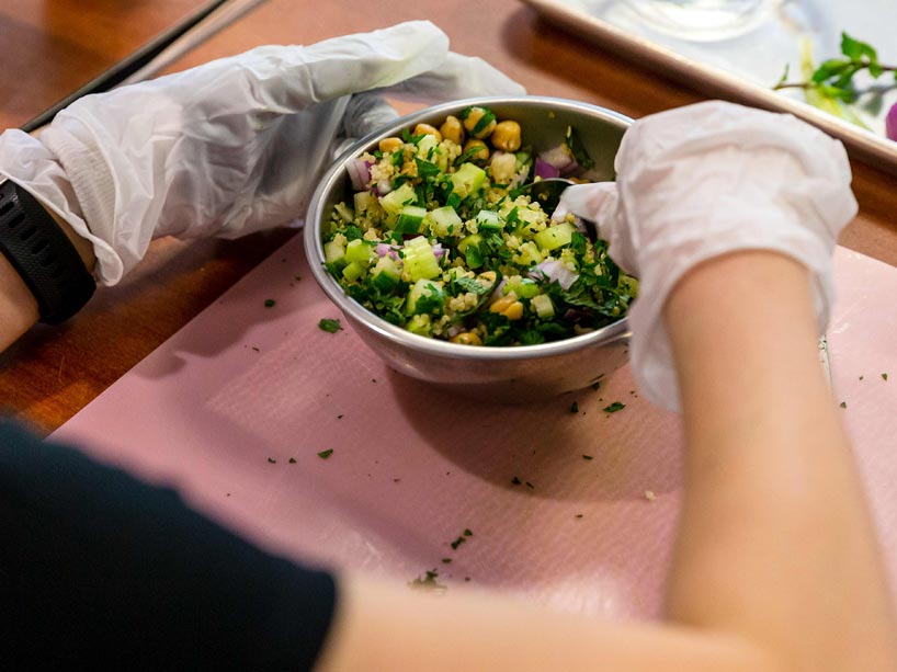 A pair of hands mixing a bowl of quinoa and vegetables