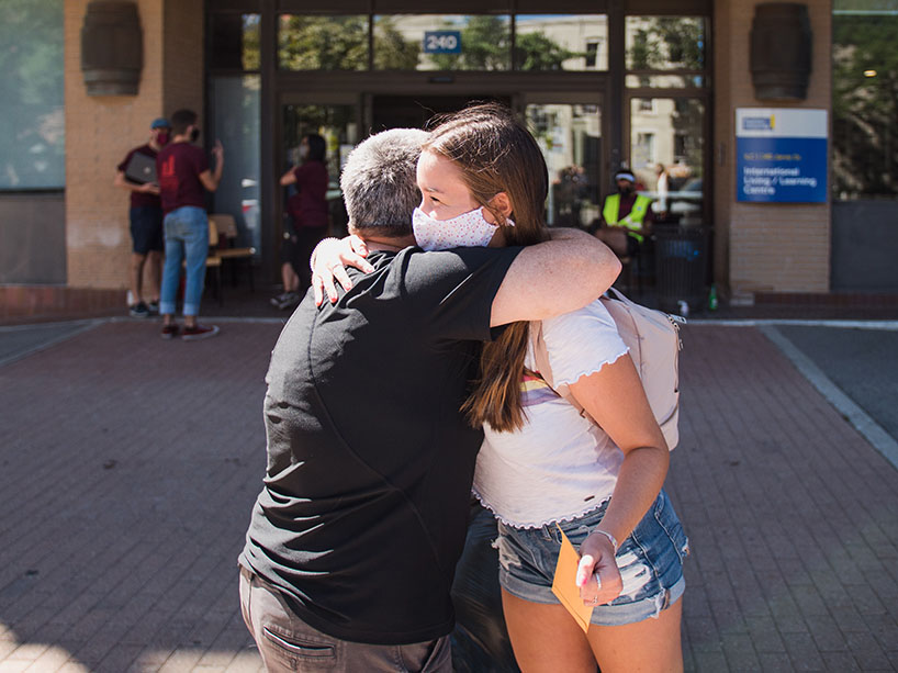 A young woman hugs her mom outside a Ryerson residence on move-in day