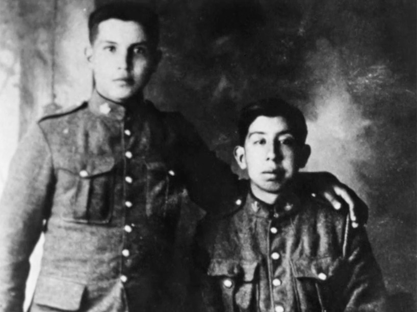 Black and white photograph of a soldier standing with his arm around a seated soldier