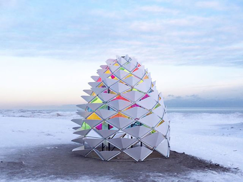 A structure, shaped like a pine cone, sits on a snow-covered beach