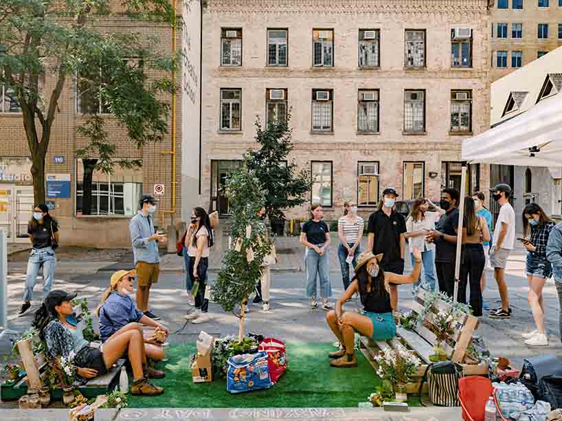 A group of people socializes on benches made out of wooden flats