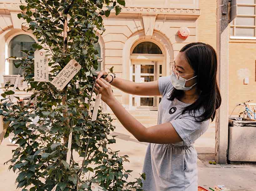 Angela Ng, co-founder of Urban Minds hangs a hand-written message on a tree