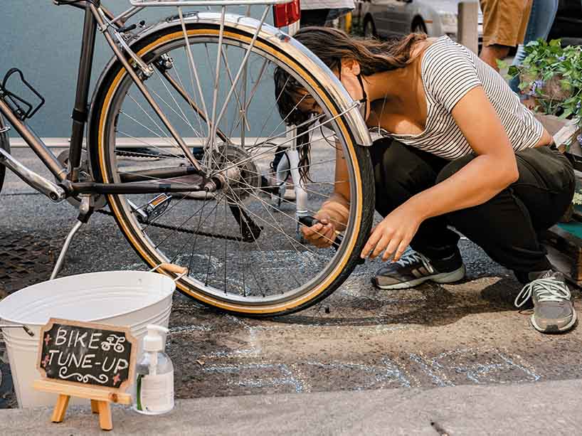 A woman adds air to a bike tire