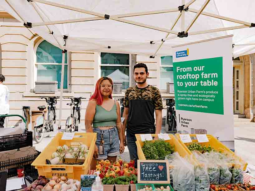 Two people stand behind fresh produce from Ryerson Urban Farm