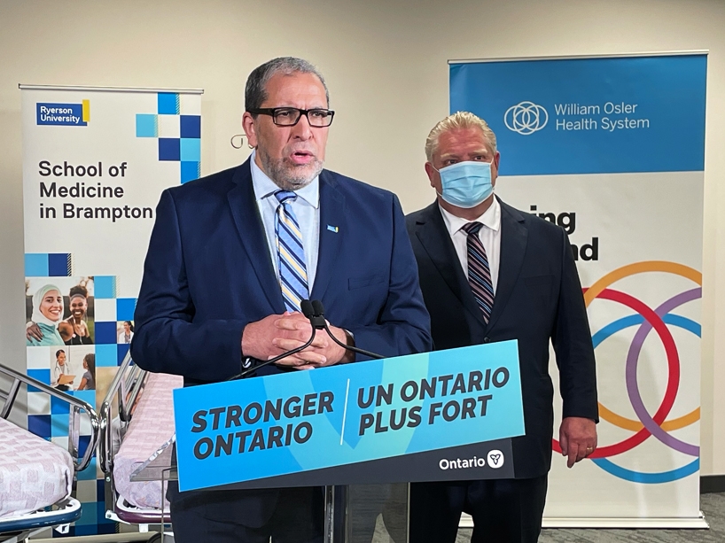 Mohamed Lachemi speaks at a press conference with Premier Doug Ford in the background.