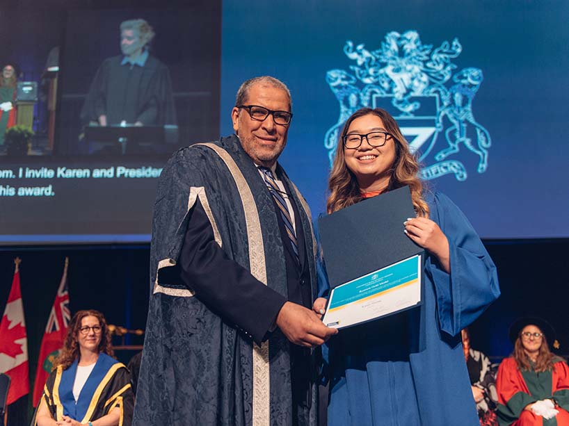 Karen Huang holding her Gold Medal award and posing for a photo with President Mohamed Lachemi.