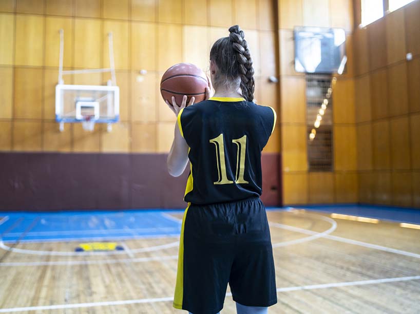 A young woman on a basketball court prepares to take a shot.