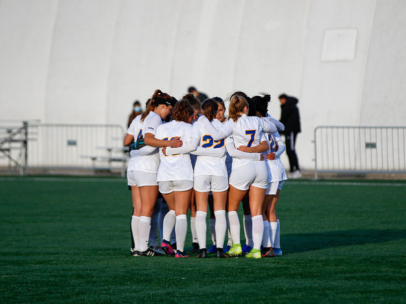 A group of soccer players huddle on the field