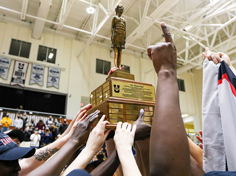 Several hands reach to touch a trophy 