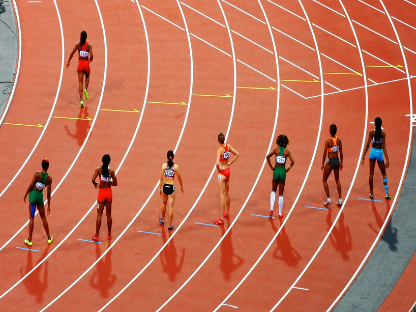 Several women take their marks on a track, with their backs to the camera.