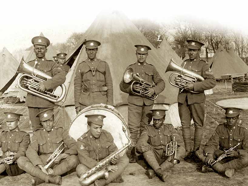 An archival photo of a group of servicemen standing outside with musical instruments.