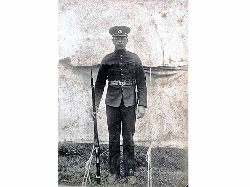 A Black serviceman standing with his rifle.