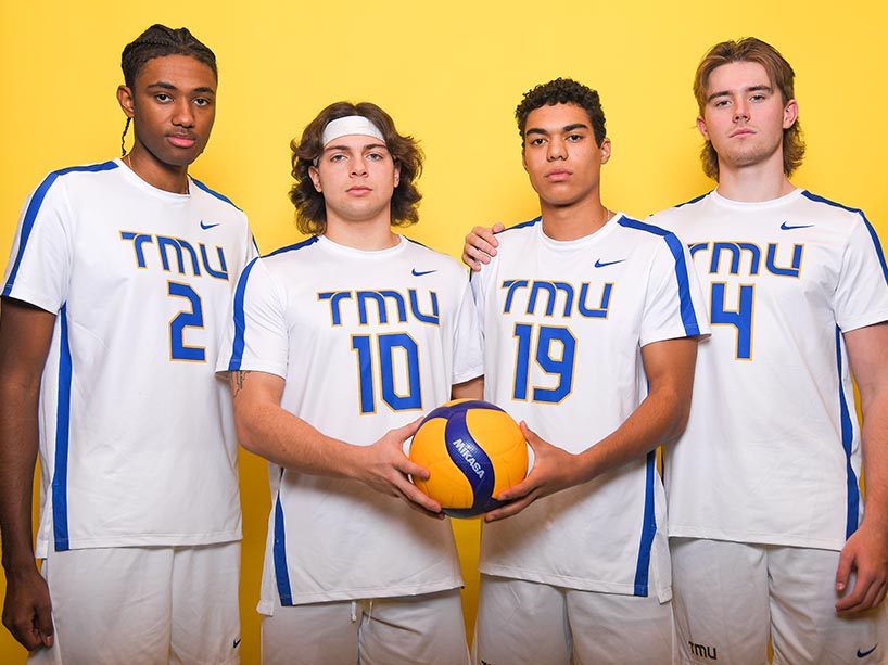 For men posing, two holding a volleyball