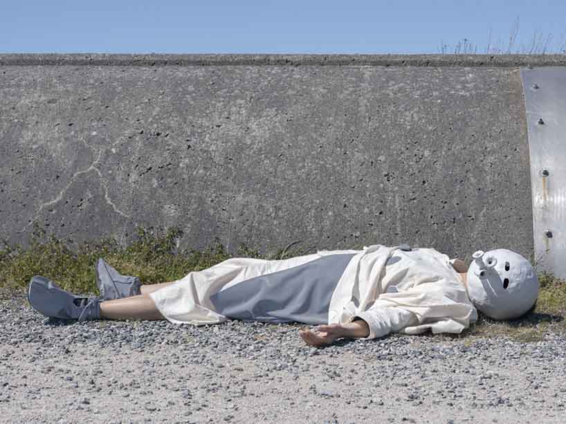 A person lying on the ground wearing a mask modelled after an emoji