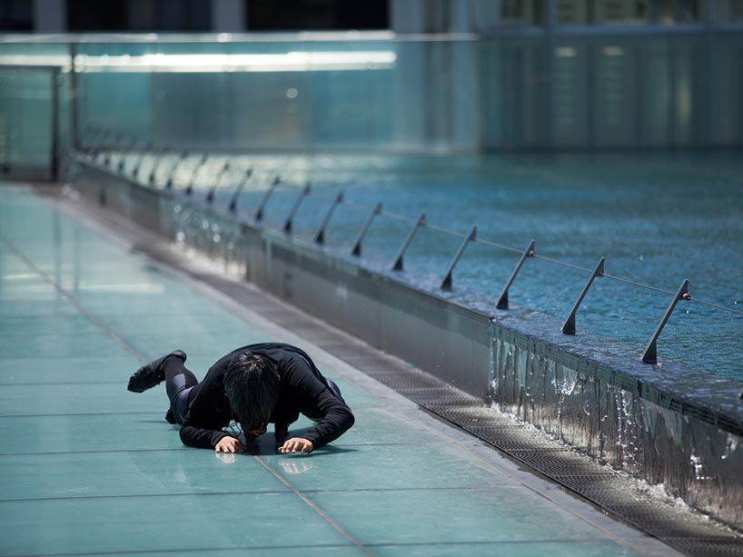 A person crawling face-down beside a fountain pool