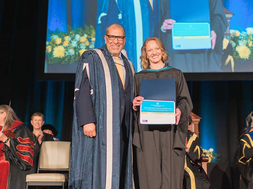 Julia Bayne accepts her Gold Medal Award from President Mohamed Lachemi on stage at convocation.