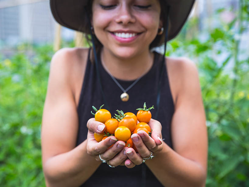A young woman holding cherry tomatoes.