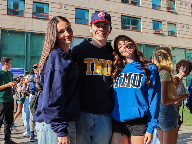 Three students wearing TMU gear