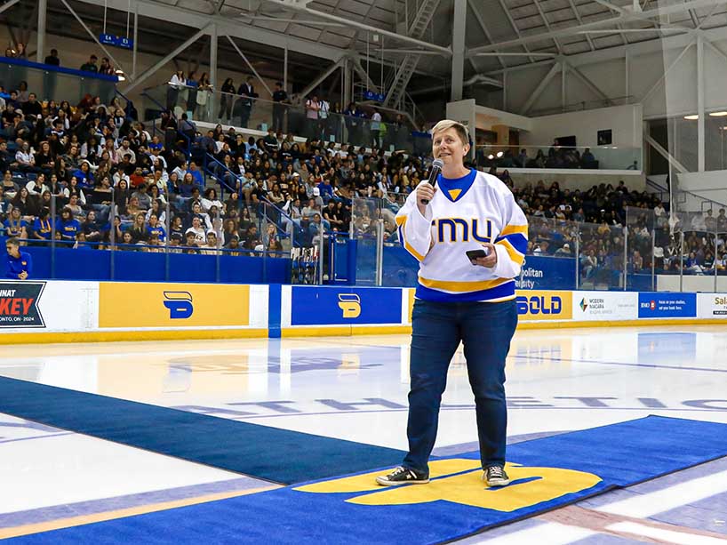 Jen McMillen standing on the ice with a microphone