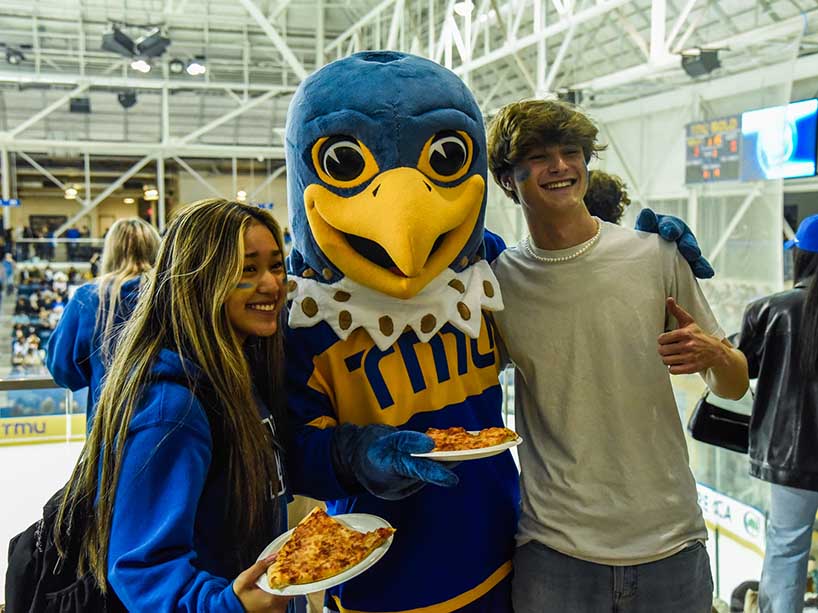 Two students pose with Frankie B. Bold, TMU’s falcon mascot