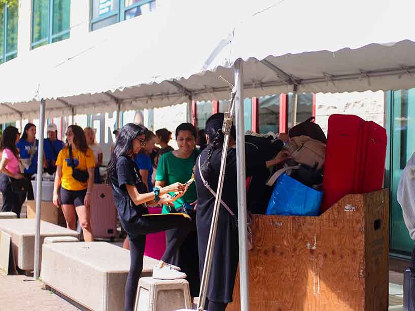 Students standing in line with suitcases.