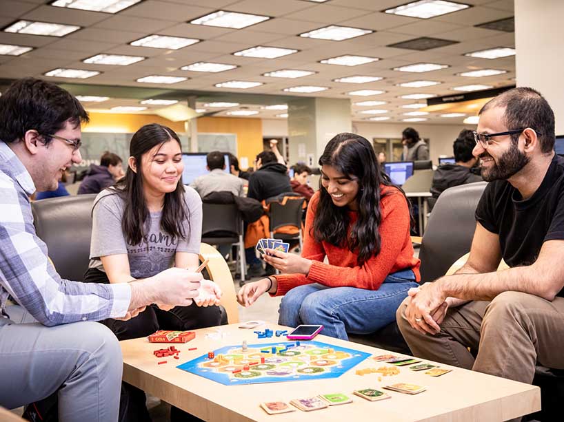 Four students playing a board game.