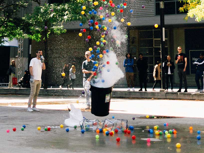 Colourful plastic balls shoot upwards out of a garbage can for a science demonstration