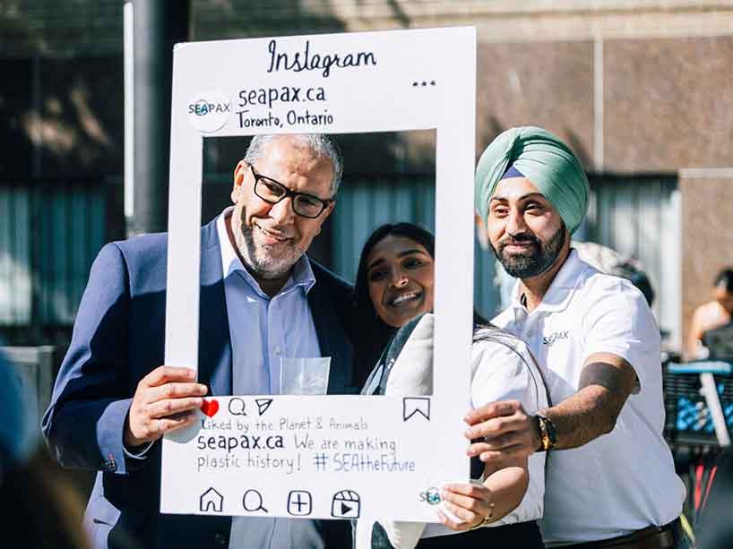 TMU President Mohamed Lachemi with two other street fair attendees in a life size Instagram frame to help promote Seapax.ca.