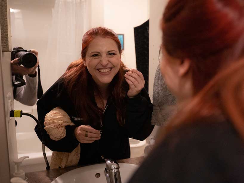 Emily Schooley smiling through her reflection in a mirror.