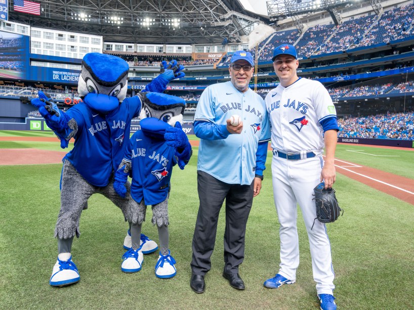 President Lachemi standing with a Blue Jays player and the Blue Jays mascots. 