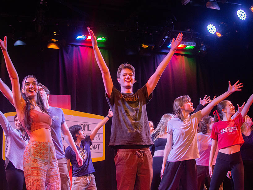 A group of students on stage, smiling at the audience.