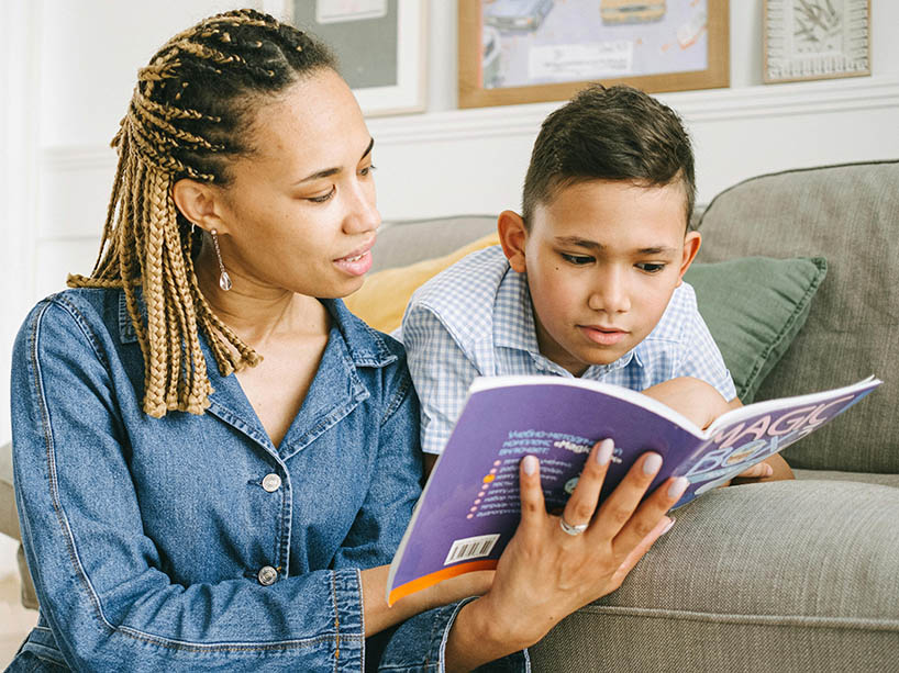 A Black mother reading a book with her son.